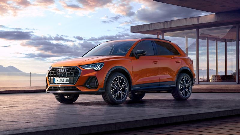 Orange Audi Q3 in a drive way with a sunset background